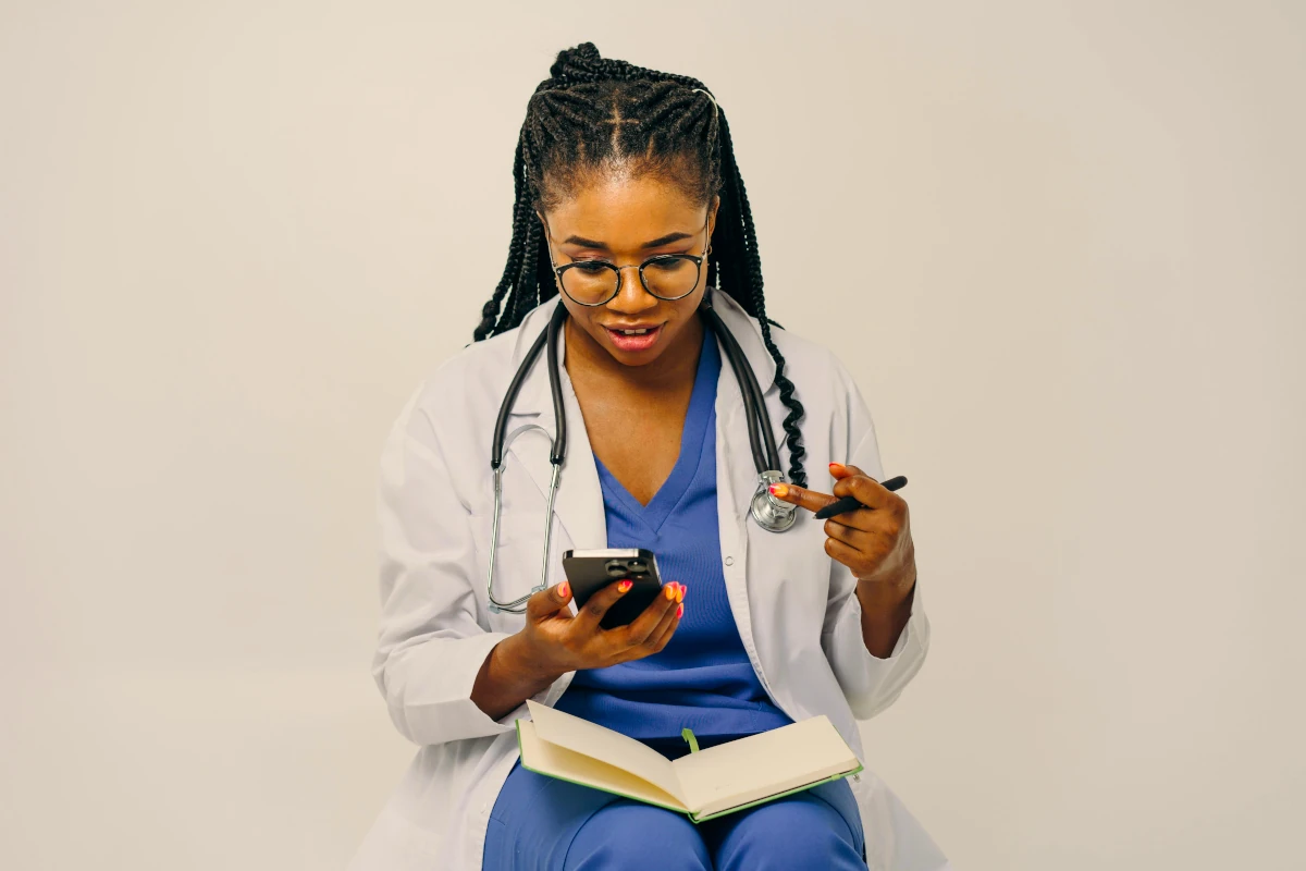 Estudiante preparado para rendir el Examen ENURM, revisando material de estudio con bata médica y un cuaderno.